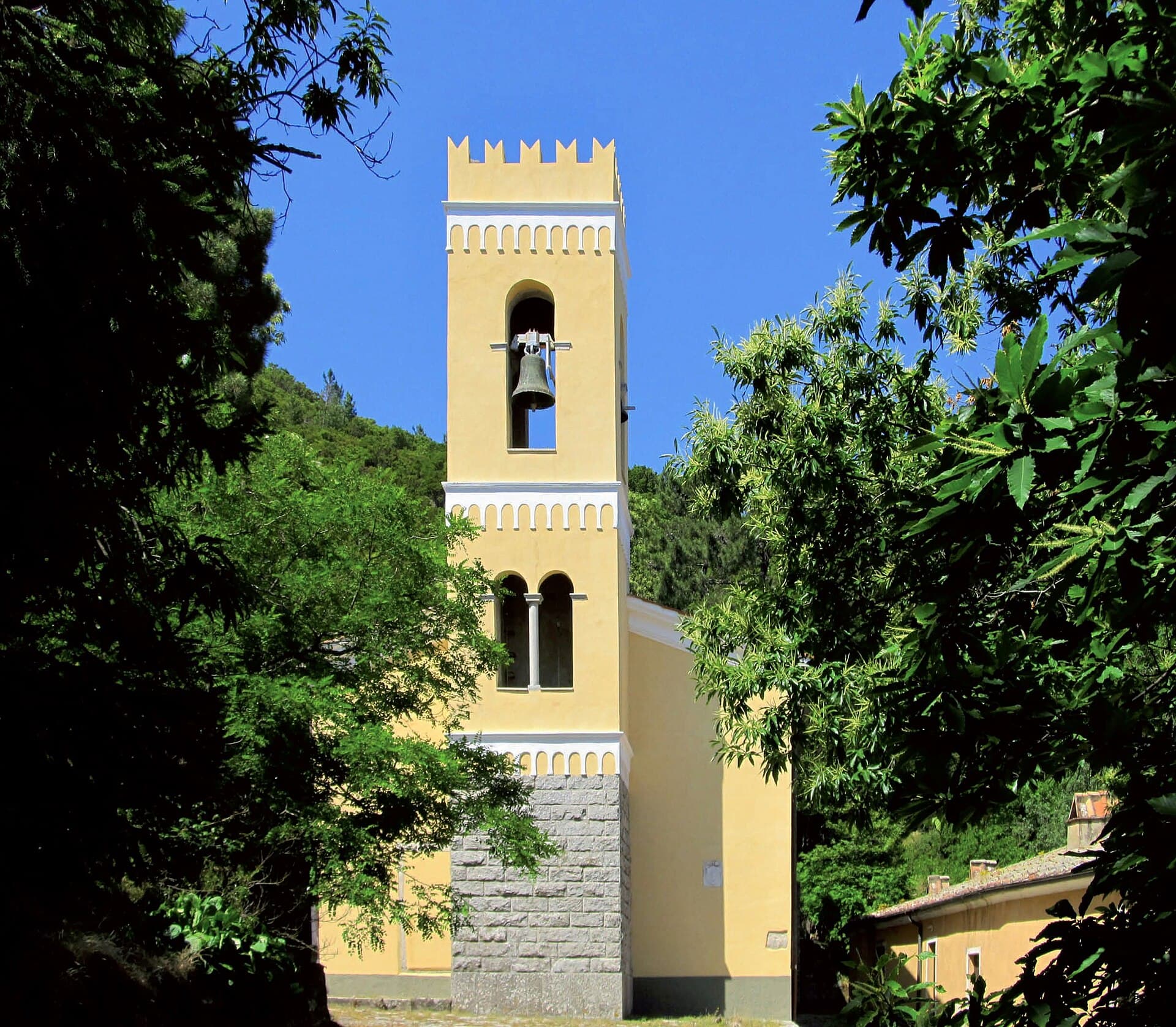 Le clocher du sanctuaire de la Madonna del Monte parmi les châtaigniers au-dessus de Marciana